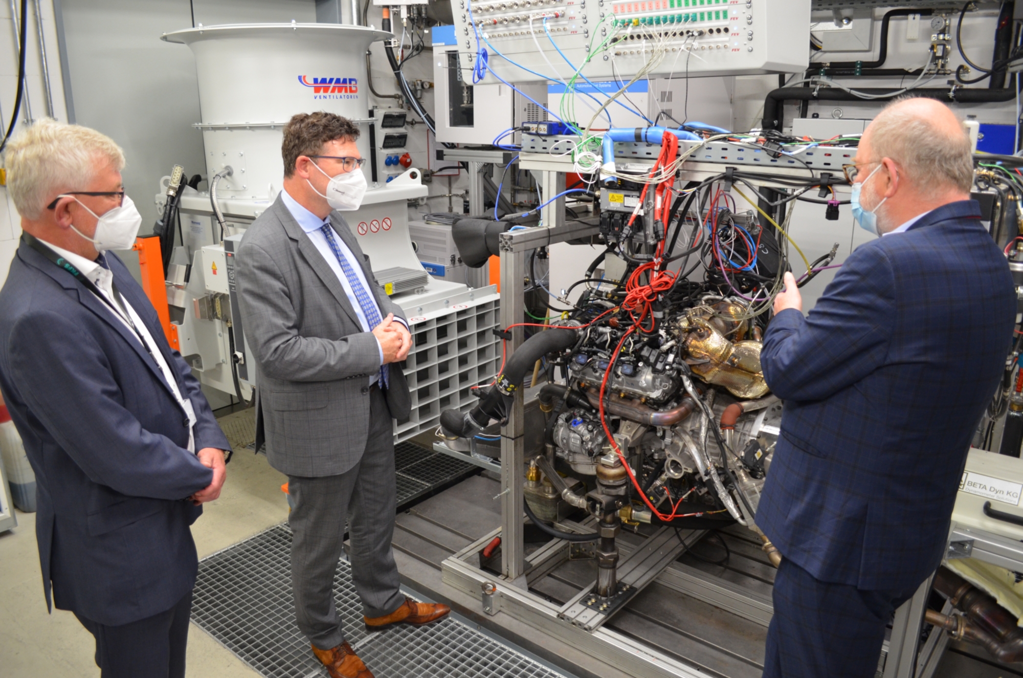 Dietmar Goericke, MdB Dr. Stefan Kaufmann und Prof. Dr.-Ing. Michael Bargende am Hybridmotorenprüfstand des Instituts für Fahrzeugtechnik Stuttgart